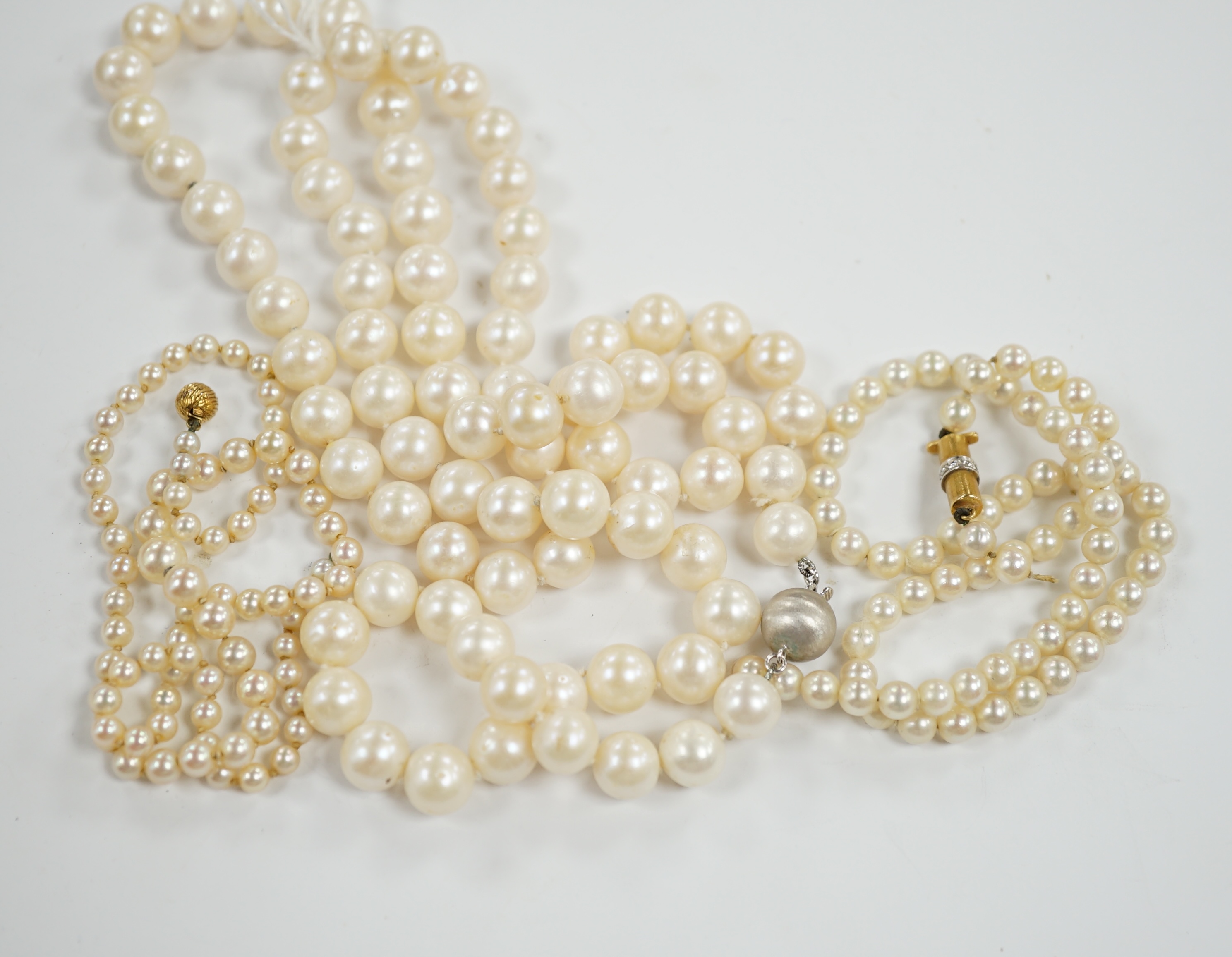 A single strand cultured pearl necklace with 18k white metal clasp, 88cm and two other similar smaller necklaces, with yellow metal clasps(both need re-stringing).